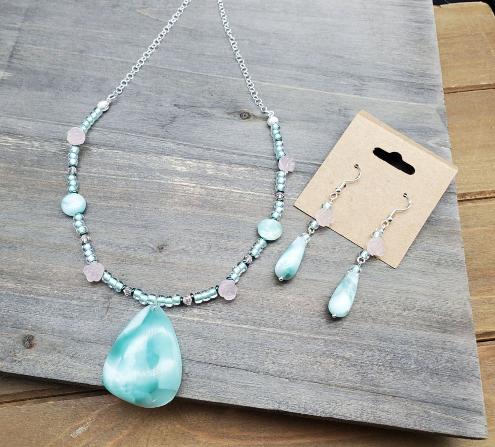 a beautiful necklace and earring set in green moonstone with a large teardrop pendant on the necklace, paired with tiny carved rose quartz rosettes.
