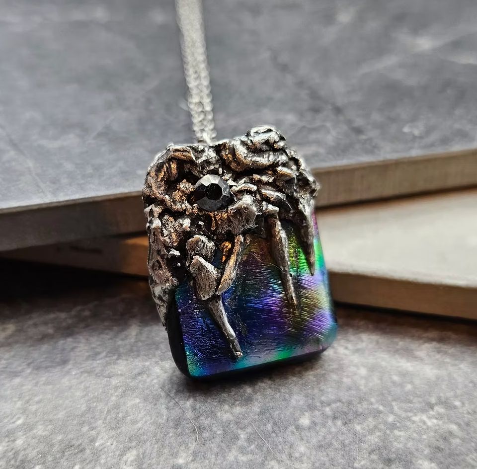 A gorgeous dichroic glass pendant with a hand fused metal bail and a black crystal. 
