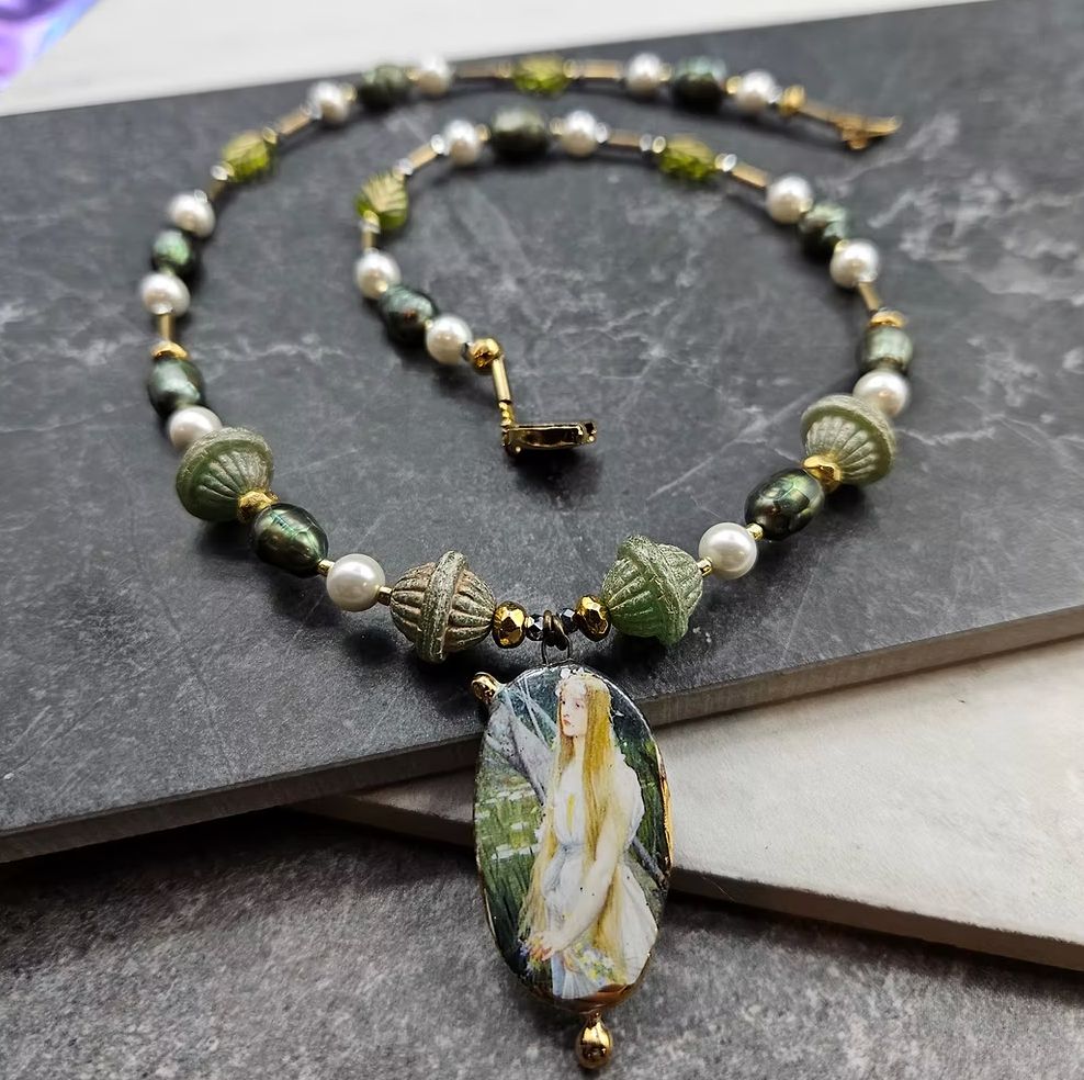 A textured bead and pearl necklace with a Parisian ceramic focal depicting a fiary 