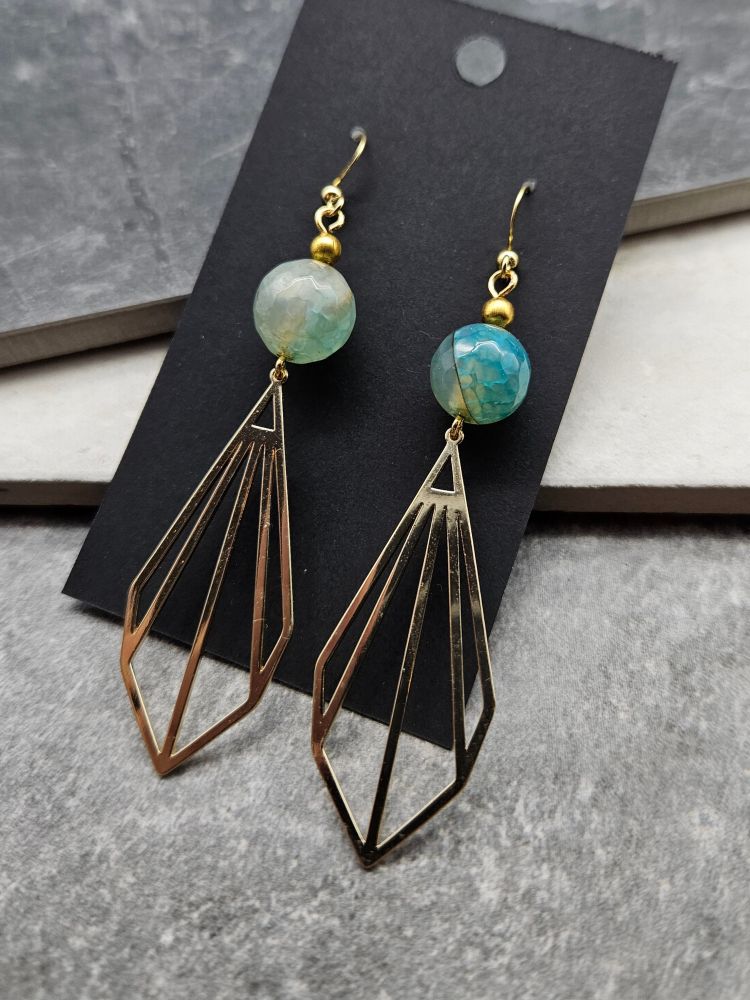 A pair of deco style earrings with a dyed teal stone and diamonds in brass.