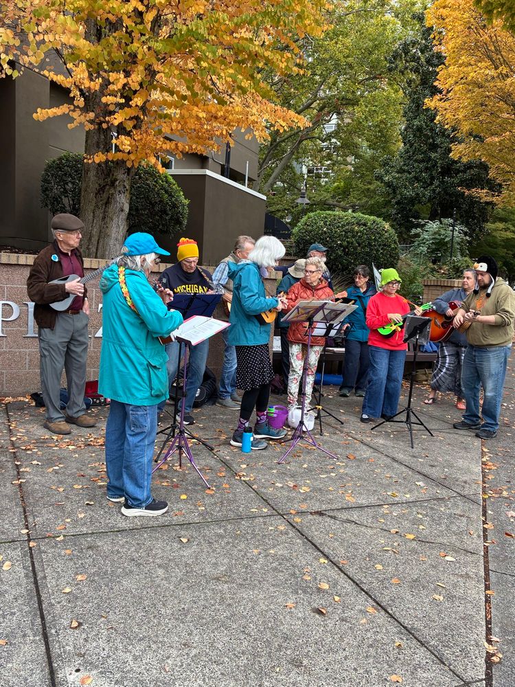 A cadre of..10-12? ukulele & guitar players lend musical support to a peaceful street action in the urban hellscape of Portland, Oregon
