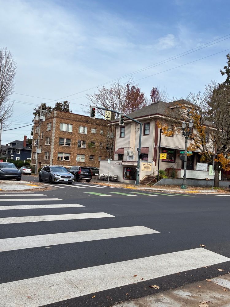 Lloyd district, NE Portland, OR: Cars, some brown-brick apartments, a white wooden building housing a nail salon & a submarine sandwich shop - all miraculously undamaged by Antifa or other urban saboteurs.