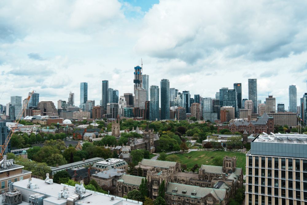 A photo of the Toronto skyline from the top of one of the University of Toronto buildings, showing the skyscrapers downtown and some of the greenery at UofT.