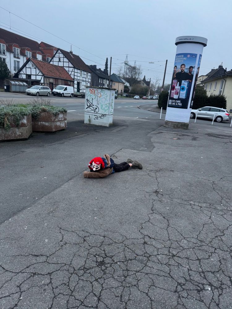 Wütendes Kind liegt auf dem Boden und trägt ein Super-Mario-Gesicht als Mütze, was es viel erträglicher macht. 