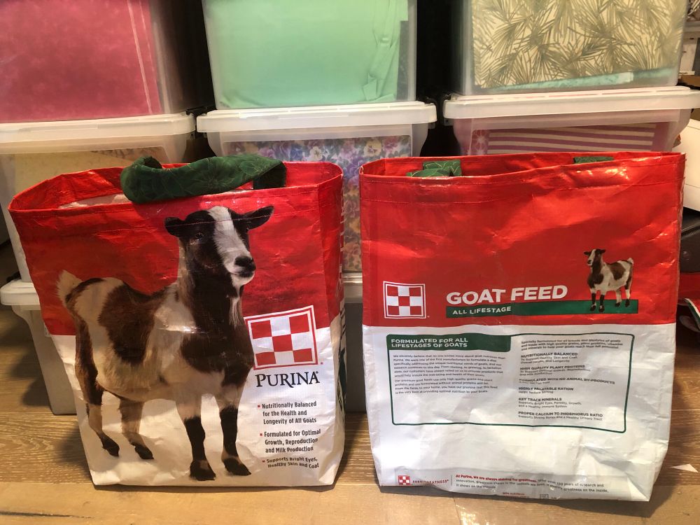 Two large tote bags made out of Purina goat feed bags. They feature a brown and white dwarf goat on the front. 