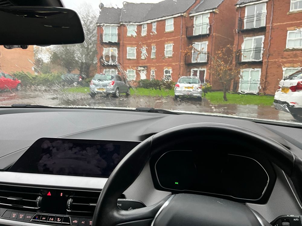 View over a car dashboard to a very very rainy scene outside. 
