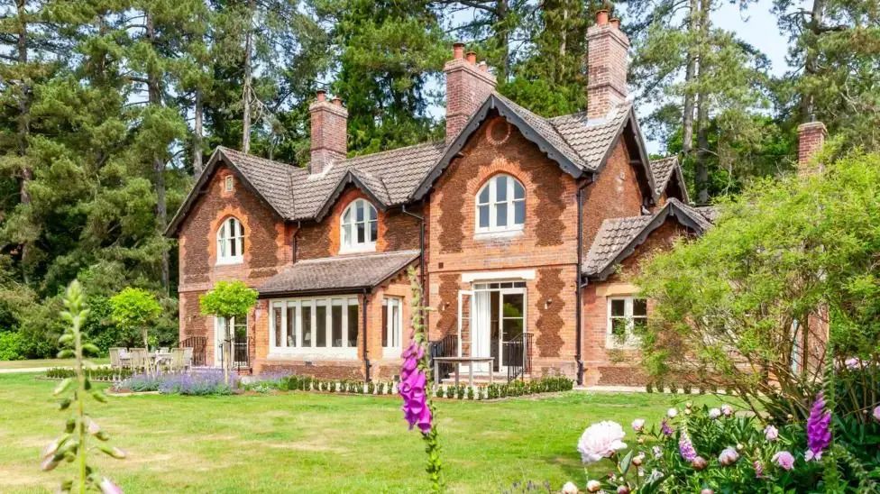 A big red brick house with three chimneys and a big garden