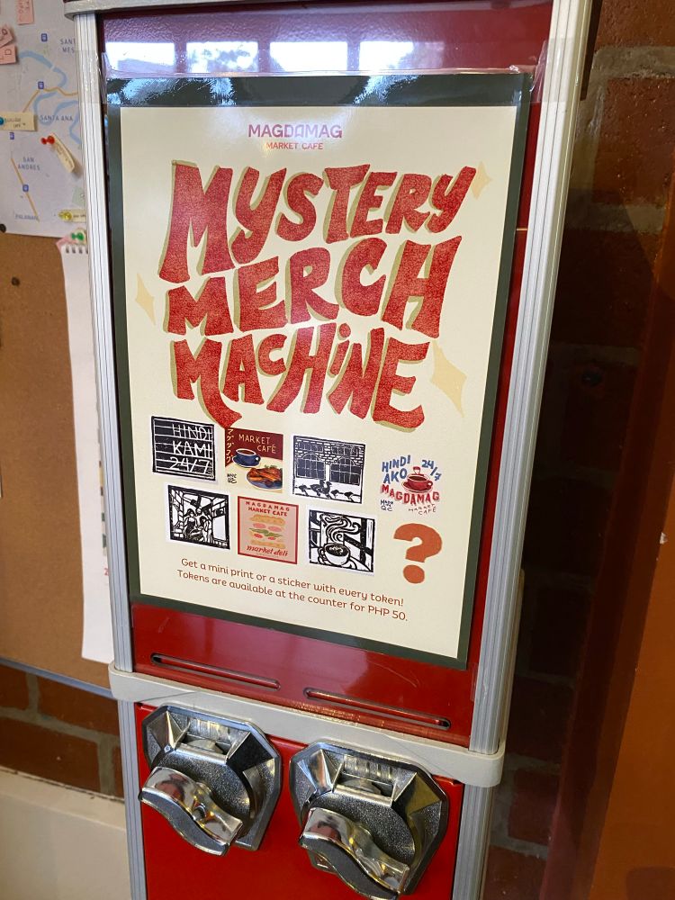 Photo of a gacha machine dispensing stickers and mini prints with special Magdamag Market Cafe designs