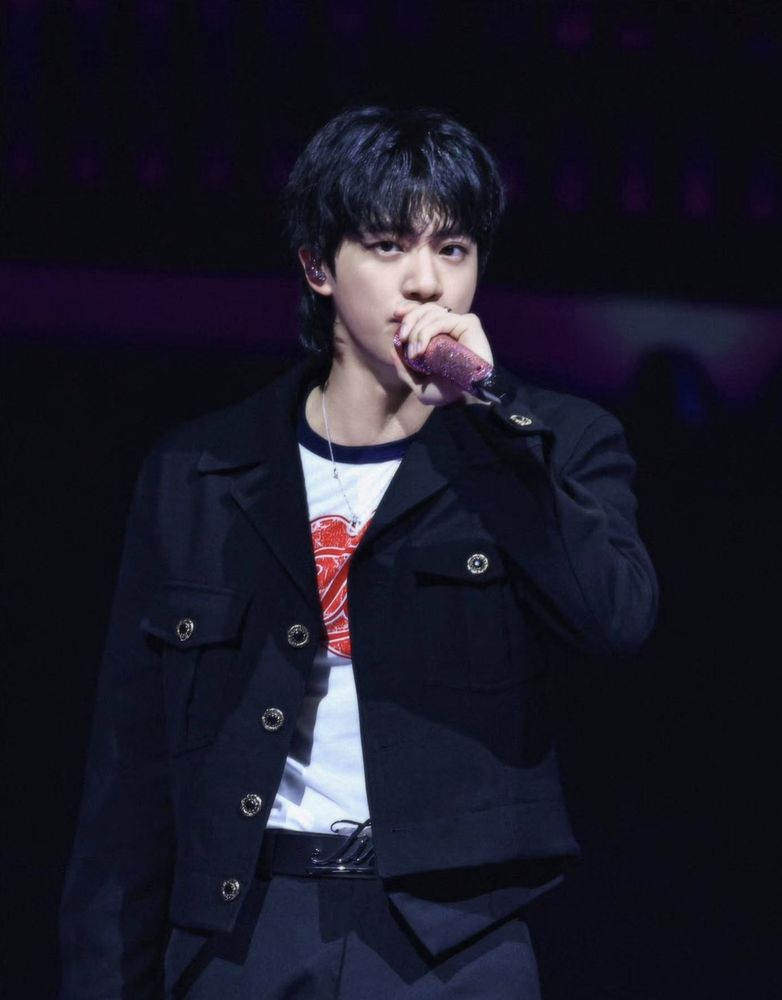 BTS Jin onstage in black jacket and pants. Just barely visible is a custom belt buckle that must say Jin. Don't question it, just go with it. 