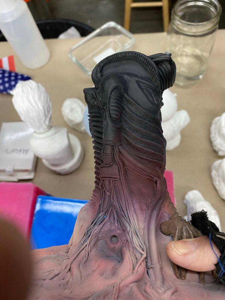 Resin maquette biomechanical body painted in an hombre like gradient from fleshy pink, to dark burgendy red, to black.