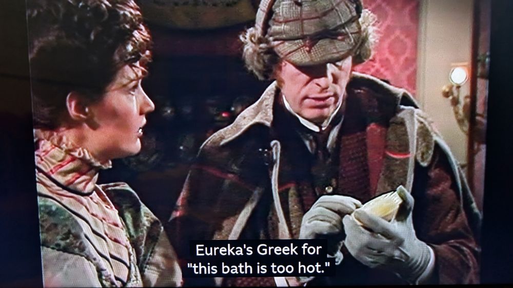 Tom Baker as Doctor Who holds a jade object while telling Leela: "Eureka's Greek for this bath's too hot."
