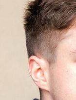 Close-up of a haircut that is very short above the ear and long on top.