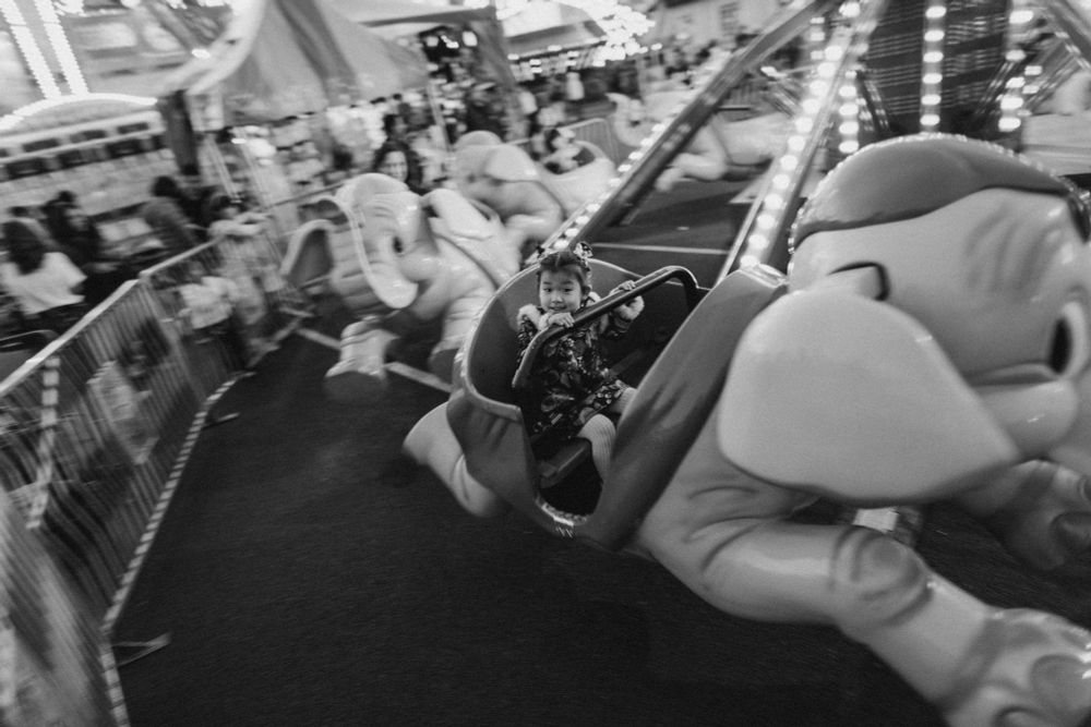 2/1: A child wearing a qipao rides a spinning carnival ride at the San Gabriel Lunar Lantern Festival. (BW)