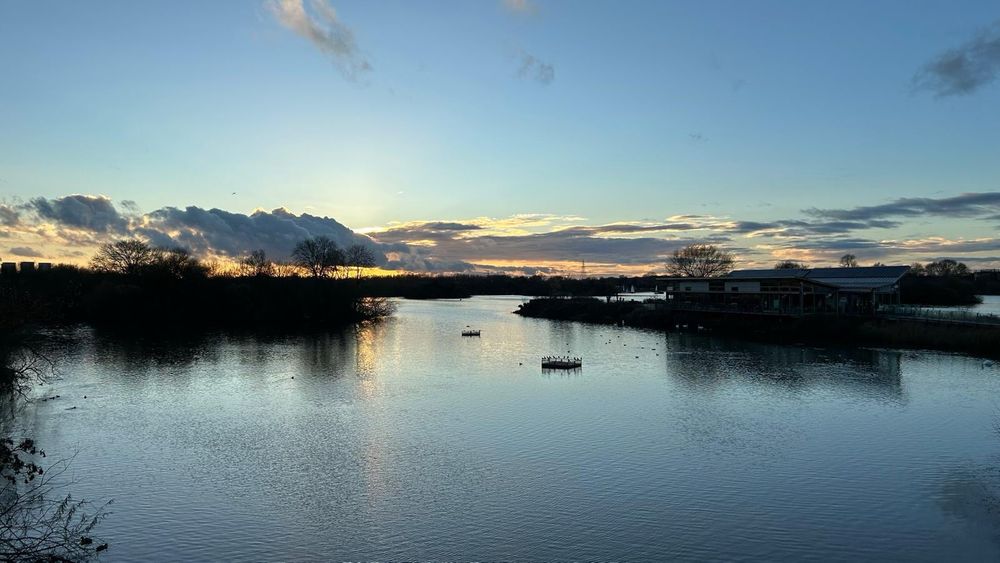 Expanse of water with clouds on the horizon hiding the setting sun