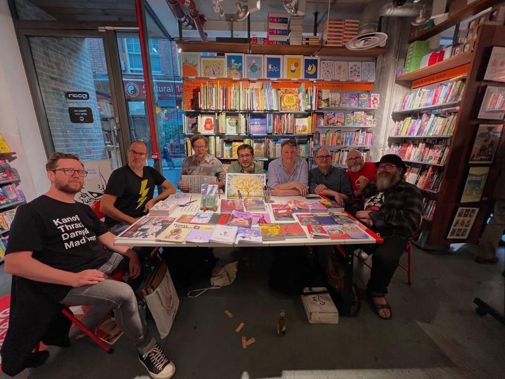 Comic creators around a table at Gosh Comics. From left to right: Dan White, Fraser Geesin, Patrick Way, John Riordan, Douglas Noble, Gareth A Hopkins, Sean Azzopardi, Mark Stafford