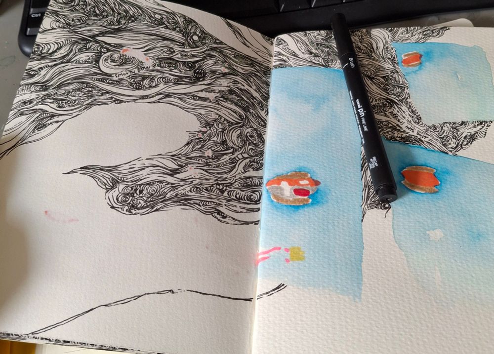 A sketchbook open with a capped pen redtingnon the right-hand page. About half of the paper is full of intricate, swirling, pointless linework or patches of blue watercolour