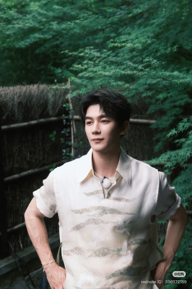 xia zhiguang standing in front of lush greenery in a white shirt with a crane print. 