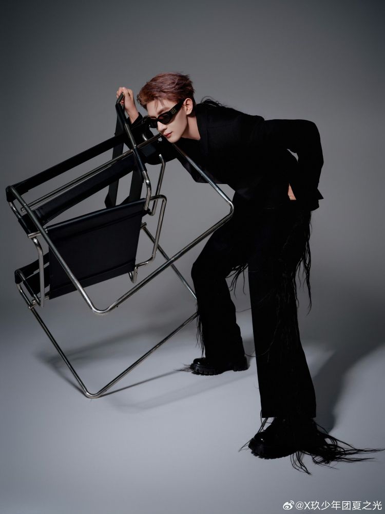 xia zhiguang in a black suit with long extensions of black hair stitched into the back of his jacket and pants legs. 