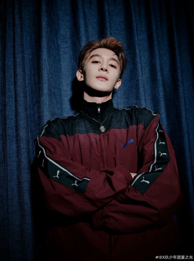 xia zhiguang with his arms crossed wearing a maroon puma sports jacket. 