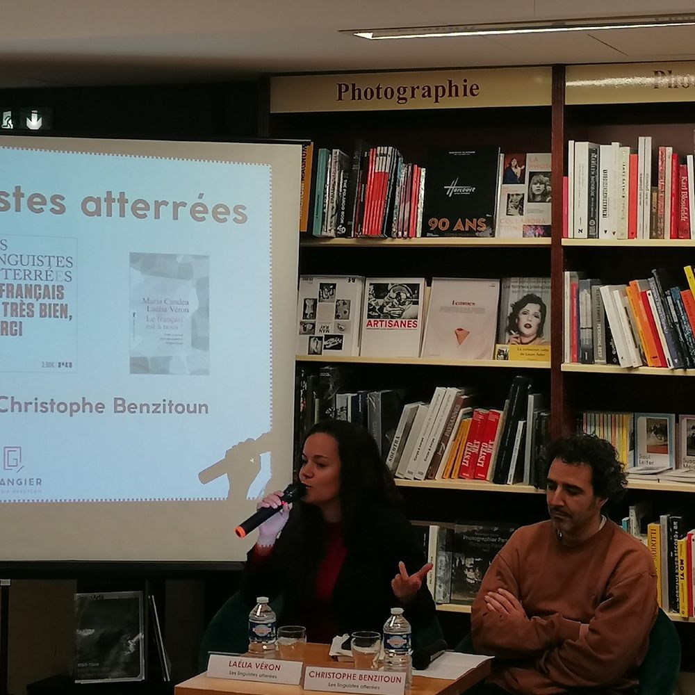 Photo de Laélia Véron et Christophe Benzitoun au micro devant une étagère pleine de livres. À côté d'eux, un écran montre des couvertures de leurs ouvrages. 