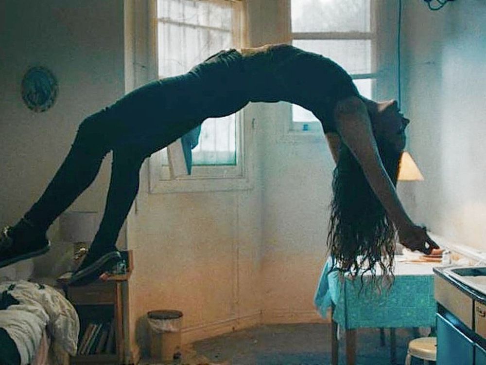 a screenshot from st maud, a woman bending backwards and hovering in the air 