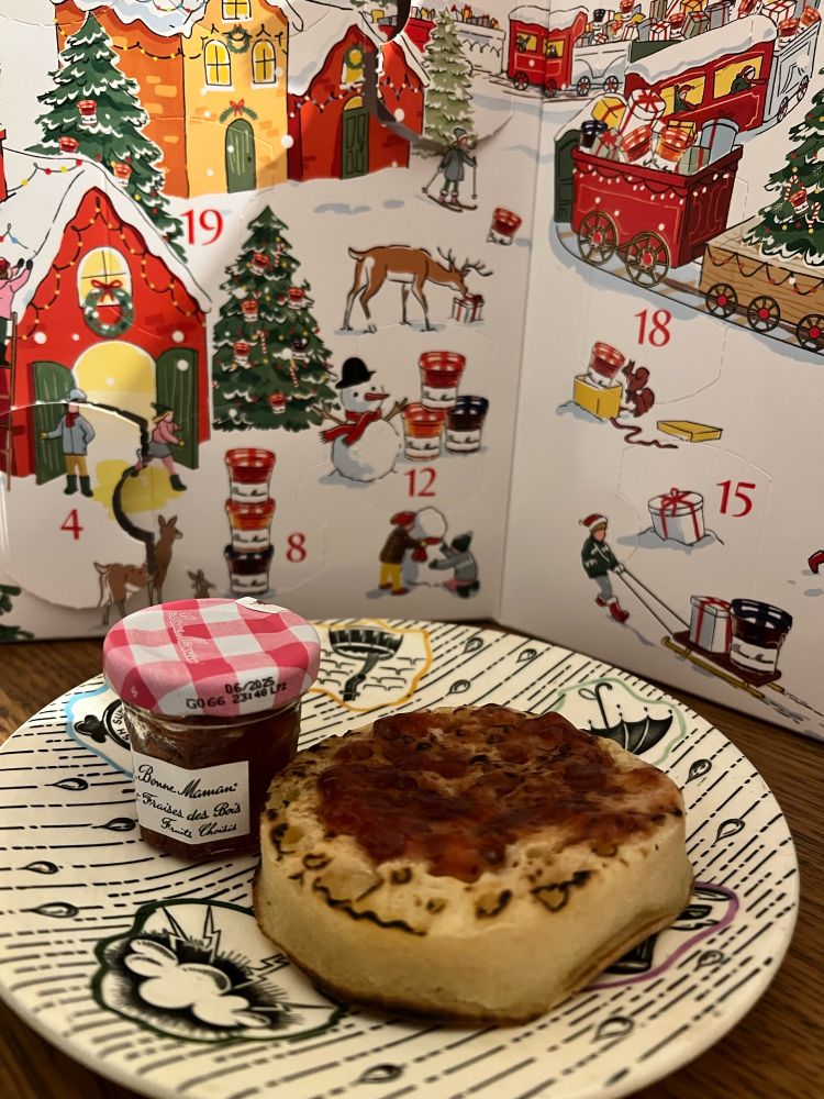 Strawberry and Wild Strawberry jam on a crumpet with the Bonne Maman advent calendar behind it 