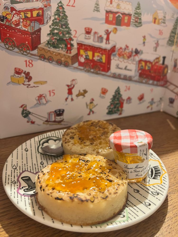 A mini jar of Bonne Maman jam with two crumpets in front of the Bonne Maman jam advent calendar
