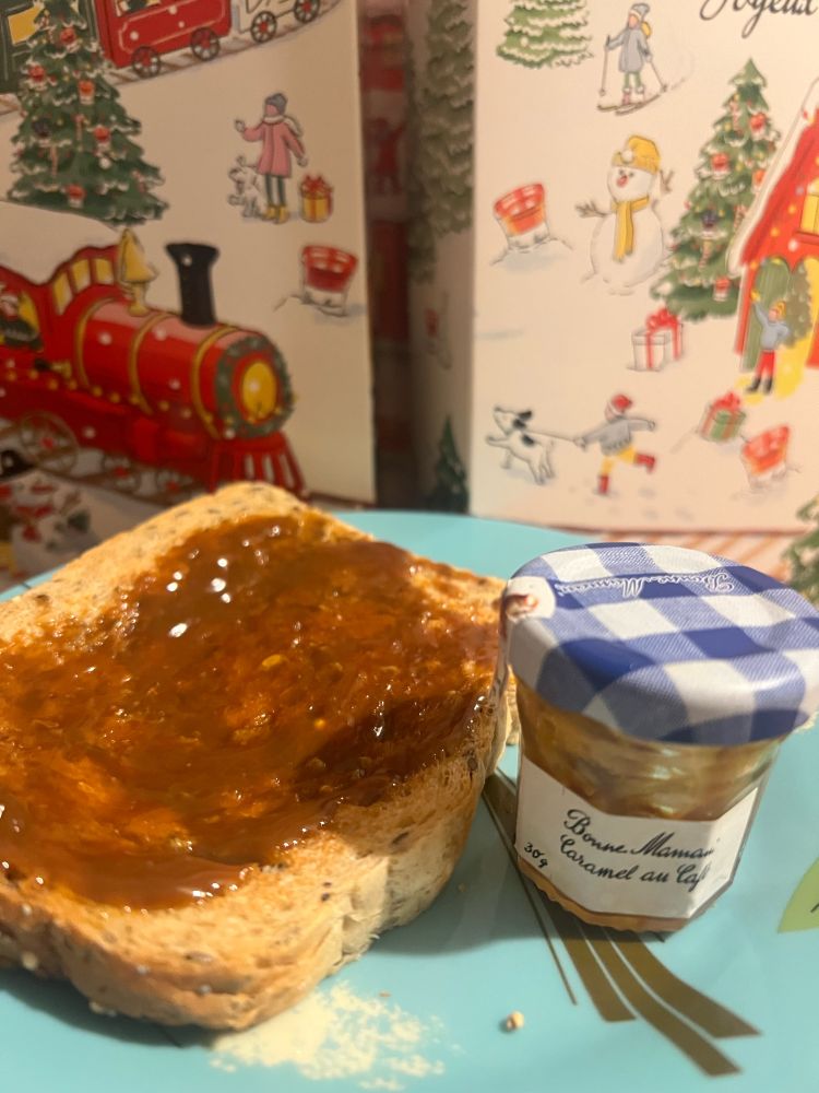 Caramel coffee spread on toast with a mini Bonne Maman jar with a blue lid, and the jam advent calendar behind 