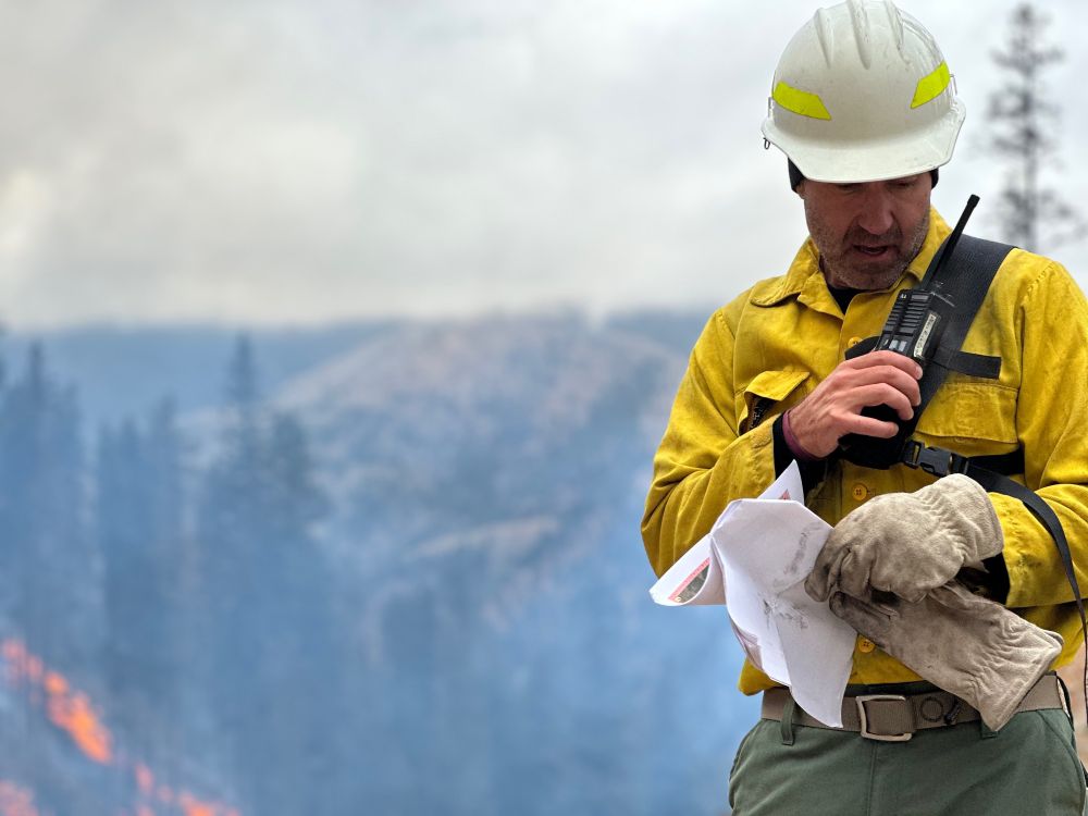 Fire crew member talks into a handheld radio.