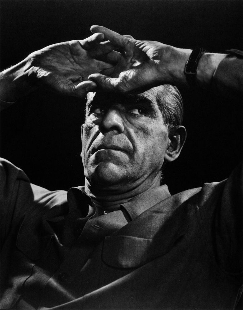 Boris Karloff in an almost relaxed position, leaning back, hands intertwined and resting on his forehead
