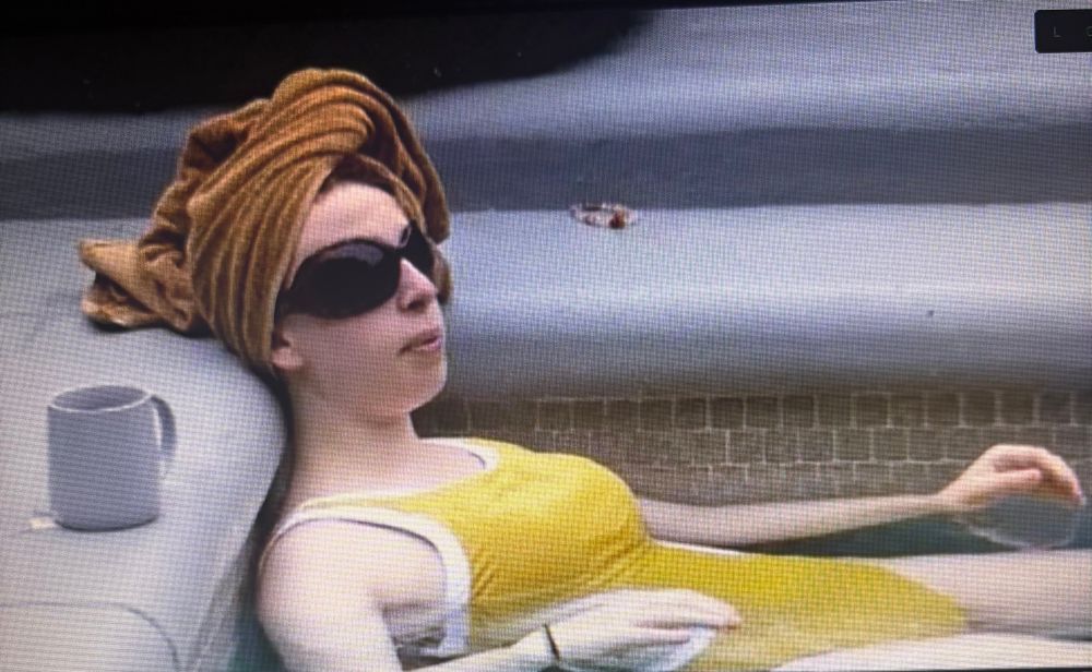 Ava bb27 in a yellow swim suit with a towel wrapped on her head and sunglasses on while laying in the hot tub 
