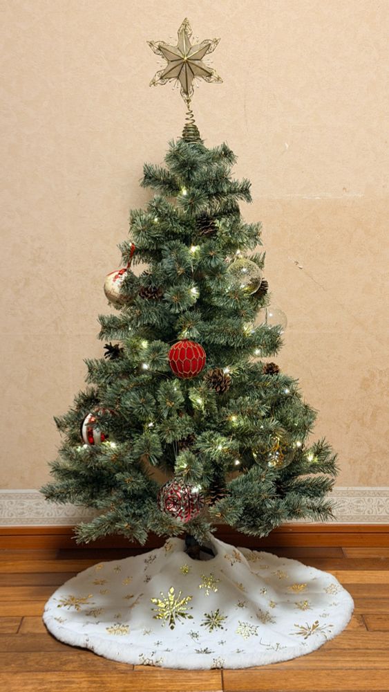 クラシックトーンのグリーンの枝ぶり、本物の松ぼっくりが元からついている素直に良いと感じたツリー。niko and...の本懐は季節雑貨にある。アパレル商品は正直少し微妙に思えるが、服が雑貨に勝ったらそれは負けという思想がある。商戦の終わりに買ったので関連商品は選択肢が少なく、トップのスターはフランフランのもの。あいにく１２０サイズのツリーには大きすぎ、重すぎという問題があって困っていたけど今年はAIに相談し解決した。スカートはAmazonで購入。商品画像は雪の結晶が刺繍っぽかったのに、現物はプリントだった。