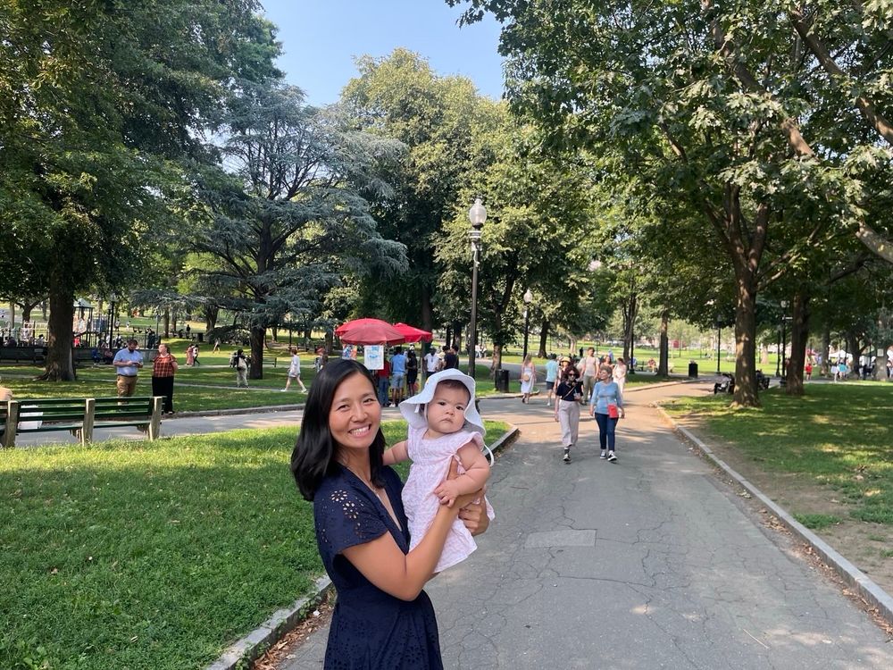 Michelle holds Mira as they walk around Boston Common earlier this afternoon, with other people walking along every visible path in the park 