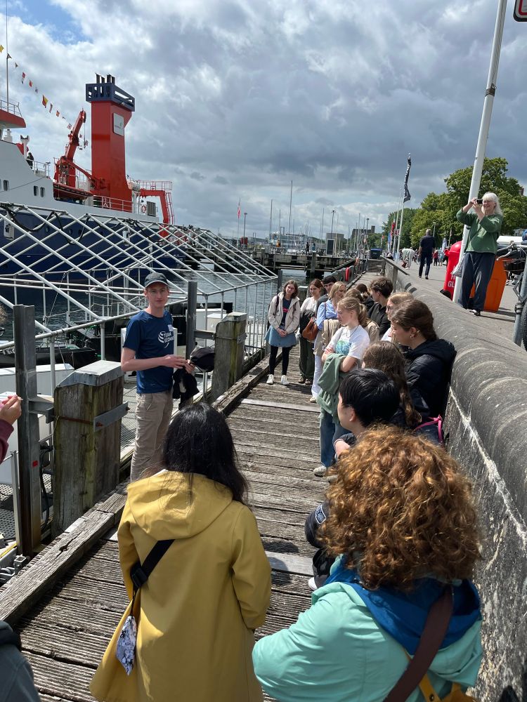 Researcher in front of mesocosm facility at Geomar explaining experment on Fucus blue carbon to Kiel Week visitors.