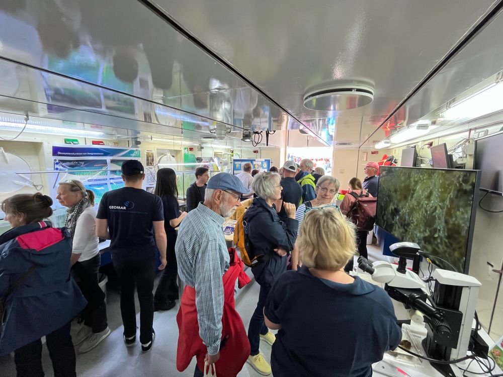 Researcher showing marine hydrozoans to visitors of RV Alkor with a microscope.