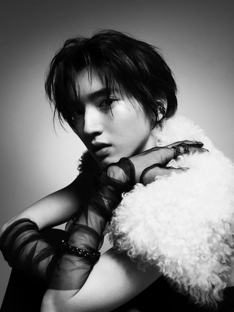 black and white photo of michieda shunsuke with long sheer black gloves and wool collar, one hand on his own shoulder and looking straight at the camera