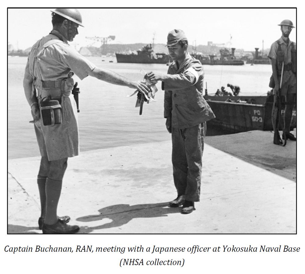 Screen grab from the Naval Historical Society of Australia Book "N Class - The Story of HMA Ships Napier, Nizam, Nestor, Norman & Nepal" by L J Lind and M A Payne. The black and white image shows CAPT Buchanan, RAN, in shorts and shirt, accepting the keys to Yokosuka naval base from a Japanese naval officer.