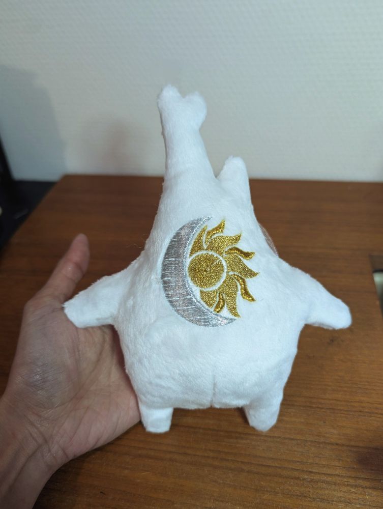 Dos d'une Peluche Korogu avec une broderie d'un logo lune - soleil 