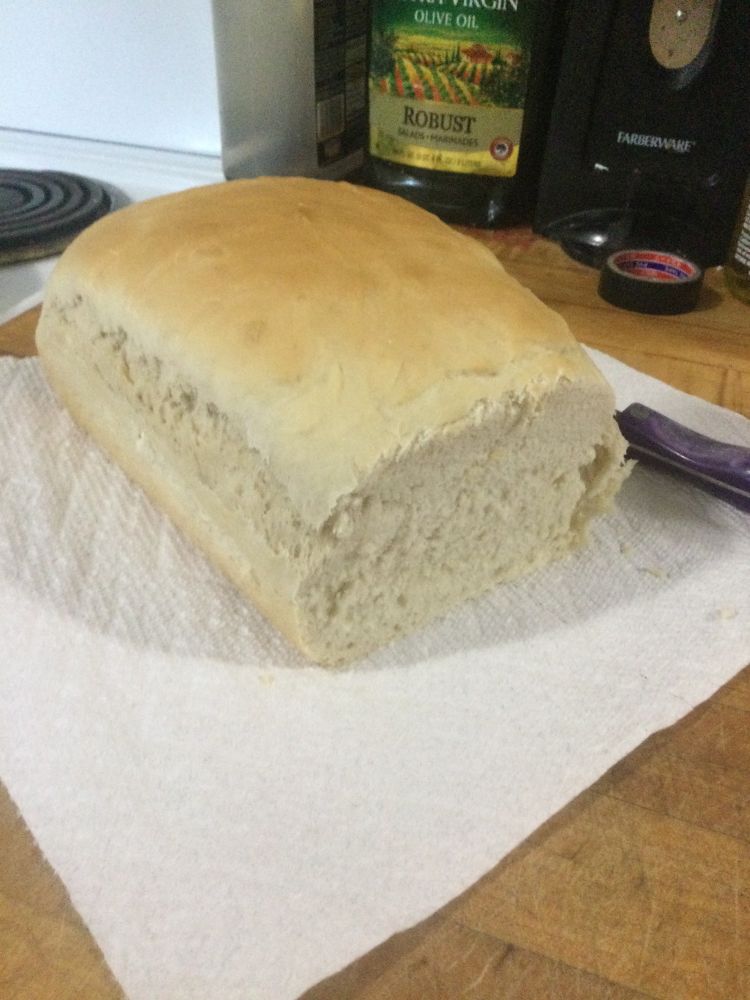 Previously mentioned bread but on a large paper towel with a slice taken out of it. Bread is slightly dense due to over kneading in the prep phase. 
