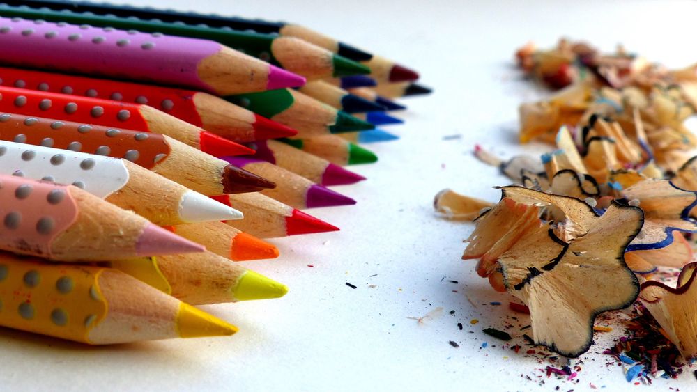 Buntstifte in vielen Farben , in zwei Reihen nach hinten gestaffelt. Rechts die bunten Anspitzspäne