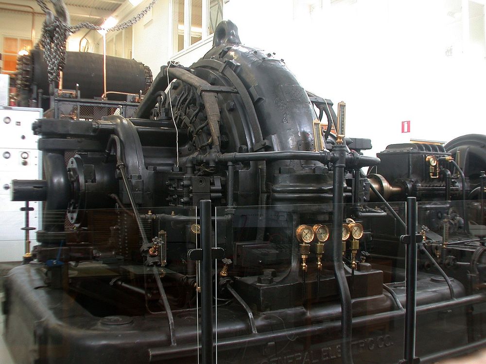 Dark hulking machine, radially symmetrical, faced with shiny brass gauges. very steampunk!

From https://en.wikipedia.org/wiki/Grimeton_Radio_Station#/media/File:Alexanderson_Alternator.jpg