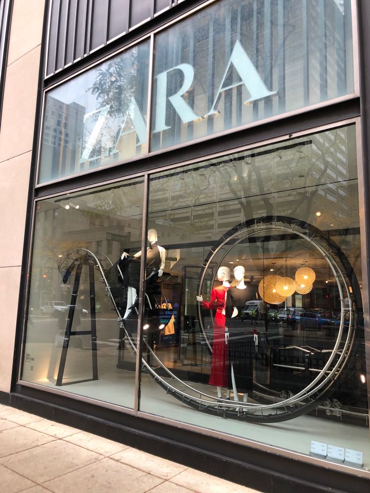 A fashion storefront in which the mannequins are riding a hilariously small roller coaster