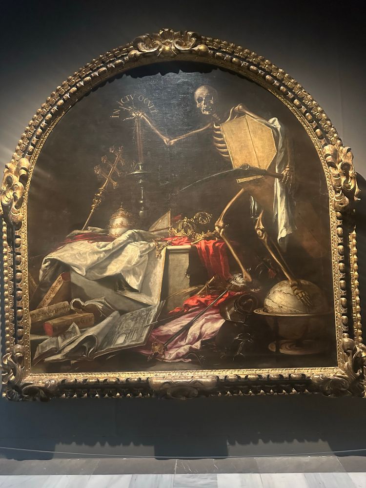 Painting of the grim reaper by Juan de Valdés Leal that shows him carrying a coffin and scythe and looming over all the earthly goods you can’t take with you 