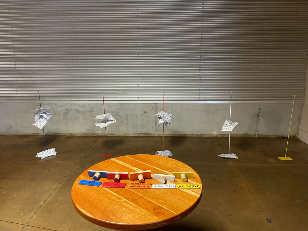 After image of the performance- table top with stamps and steel plates, showing the row of corresponding color-coded spikes (each around 3 feet tall) with incident report forms tabbed onto them.