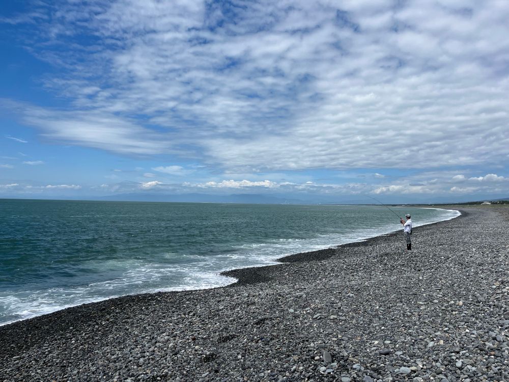 Un pêcheur sur une plage de galets 