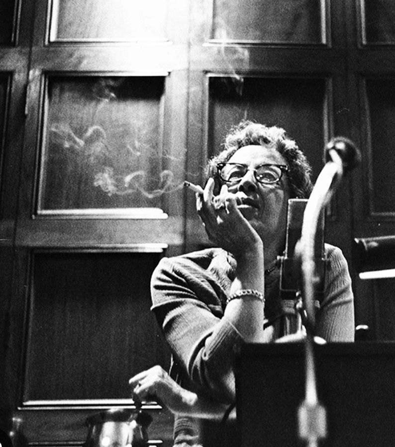 Hannah Arendt nach einer Vorlesung hinter Mikro, mit Kippe in der Hand