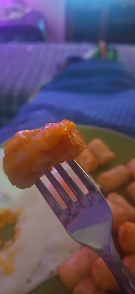 A potato gem dipped in egg sits on the end of a fork. 