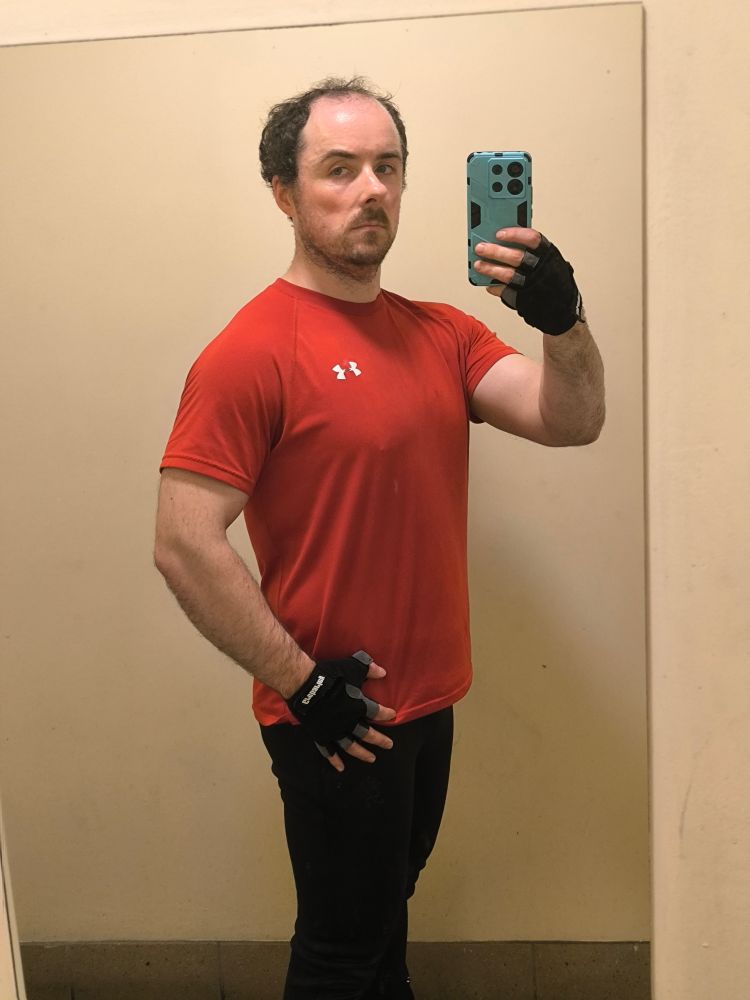 Mirror selfie of myself in a red t-shirt in the gym after my workout.