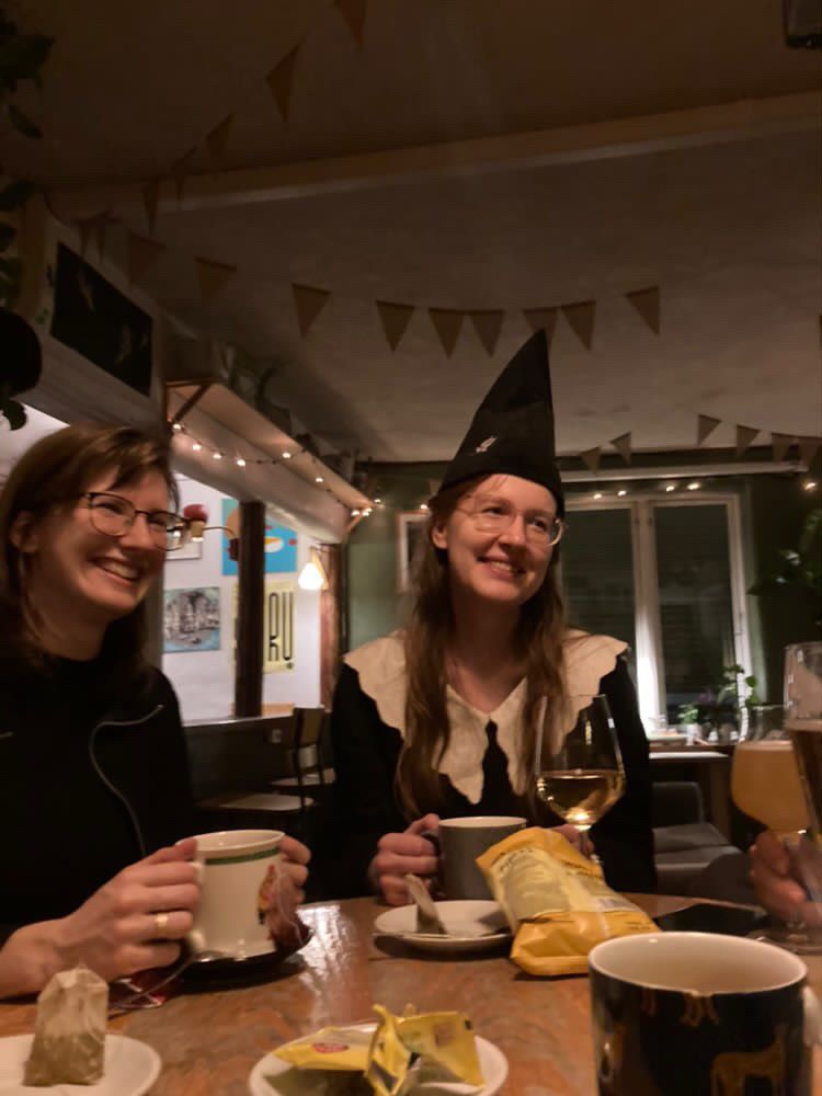 two girls in a nice bar, smiling, one of them wearing a Ravenclaw hat