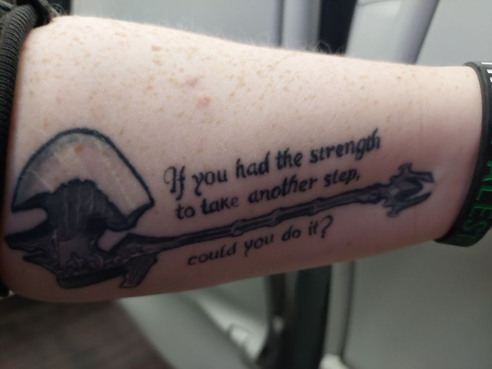 My pale, freckled left forearm with a tattoo of an impressive axe, specifically Ardbert's axe from Final Fantasy 14, with the quote "If you had the strength to take another step, could you do it?"